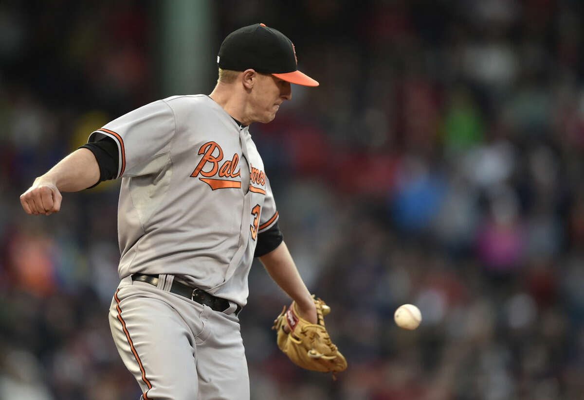 Baltimore Orioles relief pitcher Brad Brach reaches for the ball as he runs toward first after a hit by Boston Red Sox's Brock Holt in the seventh inning of a baseball game, Saturday, April 18, 2015, in Boston. (AP Photo/Gretchen Ertl)