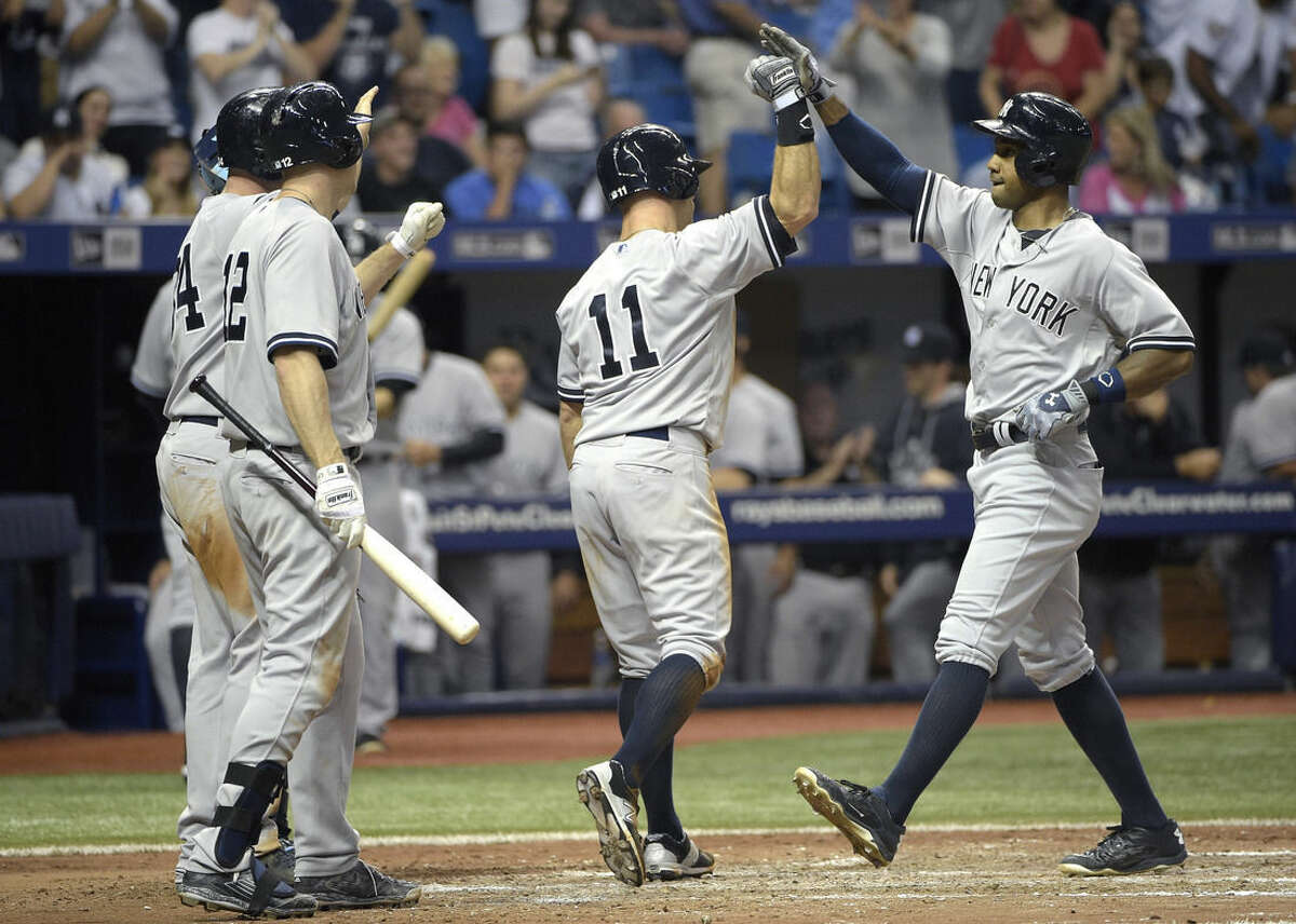 New York Yankees' Chris Young, right, is congratulated by Brian McCann, left, Chase Headley (12) and Brett Gardner (11) after hitting a grand slam during the seventh inning of a baseball game against the Tampa Bay Rays in St. Petersburg, Fla., Saturday, April 18, 2015.(AP Photo/Phelan M. Ebenhack)
