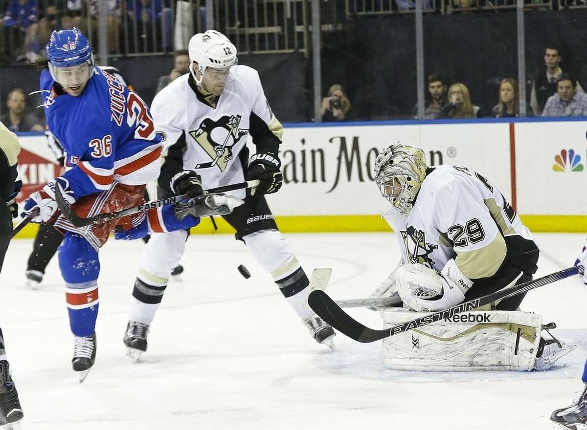 Pittsburgh Penguins goalie Marc-Andre Fleury (29) stops a shot on goal as teammate Ben Lovejoy (12) and New York Rangers' Mats Zuccarello (36) watch during the second period of Game 2 in the first round of the NHL hockey Stanley Cup playoffs Saturday, April 18, 2015, in New York. (AP Photo/Frank Franklin II)
