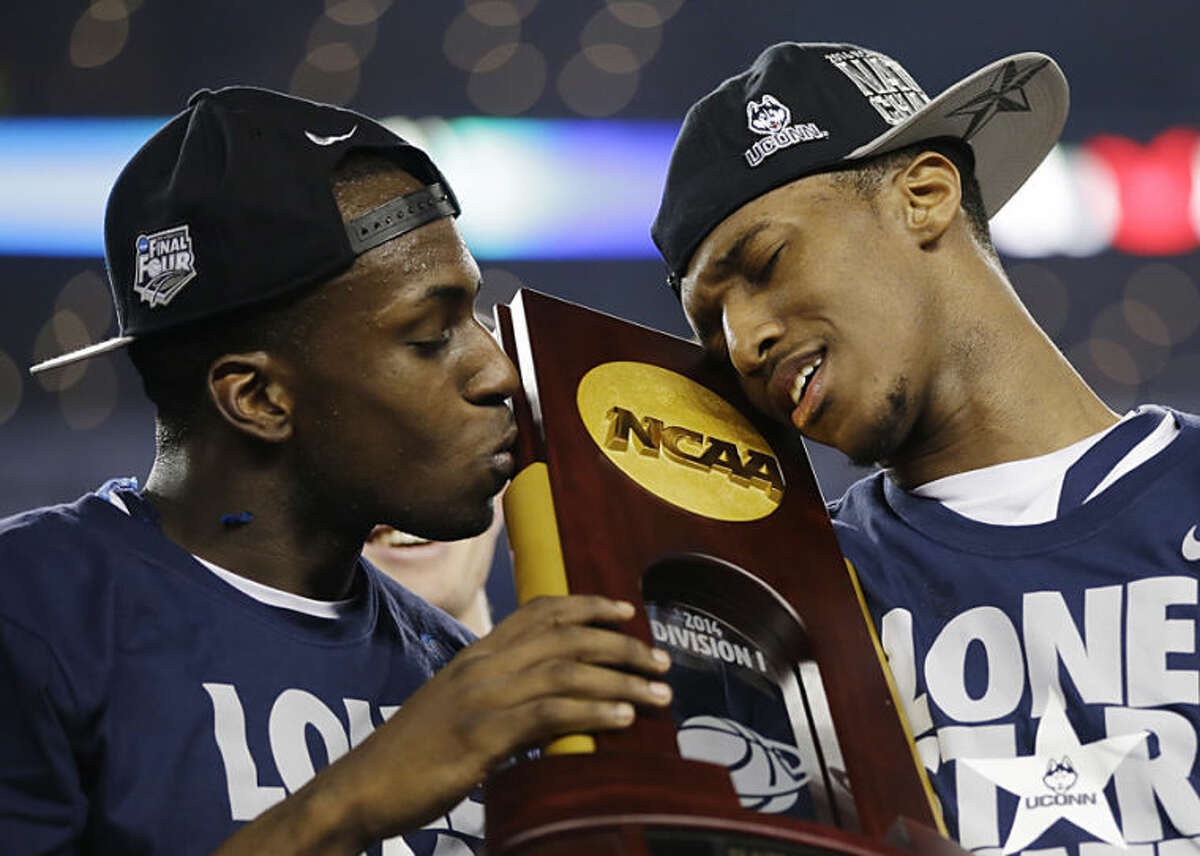 Connecticut guard Terrence Samuel, left, and guard Lasan Kromah hold the championship trophy after beating Kentucky 60-54, at the NCAA Final Four tournament college basketball championship game Monday, April 7, 2014, in Arlington, Texas. (AP Photo/David J. Phillip)