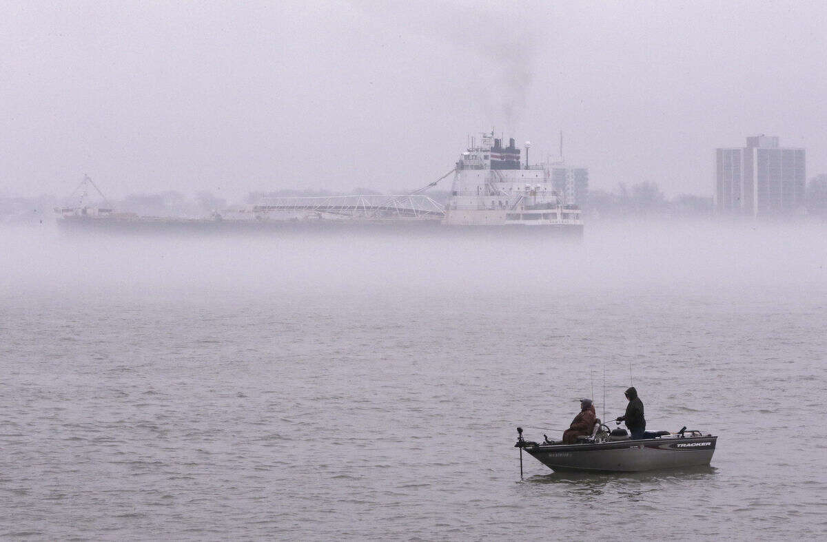 Fishermen cast their lines in the Detroit River as the Sam Laud, an iron ore freighter, travels through the fog, Monday, April 11, 2016, in Detroit. (AP Photo/Carlos Osorio)