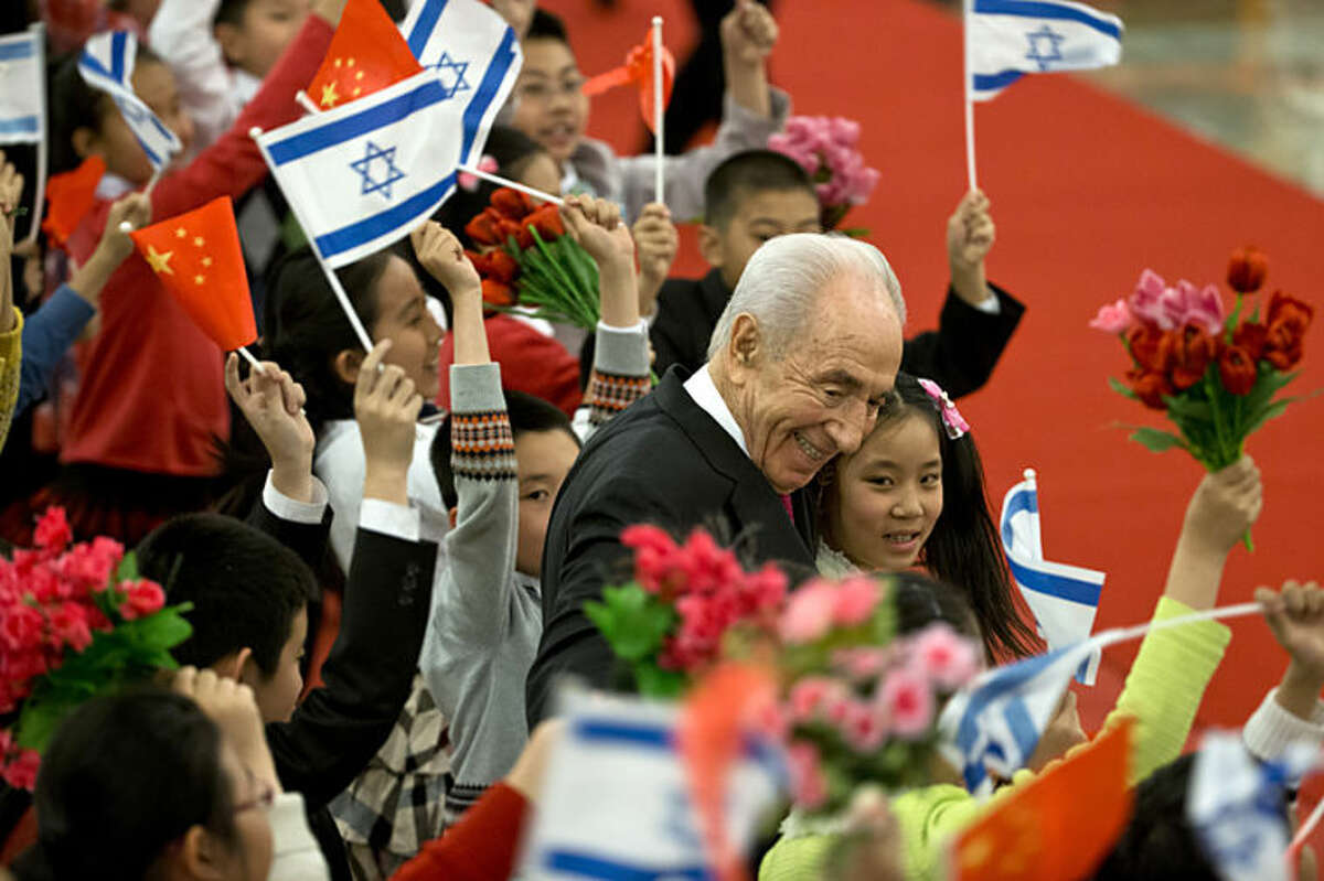 Israeli President Shimon Peres, center, hugs Chinese children during a welcome ceremony held by Chinese president Xi Jinping at the Great Hall of the People in Beijing Tuesday, April 8, 2014. (AP Photo/Alexander F. Yuan)