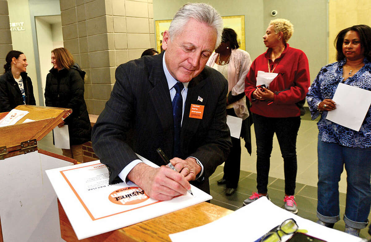 Hour photo / Erik Trautmann Norwalk Mayor Harry Rilling signs a pledge against racsim during the YWCA of Darien and Norwalk event, Stand Against Racism, at Norwalk City Hall Friday morning.