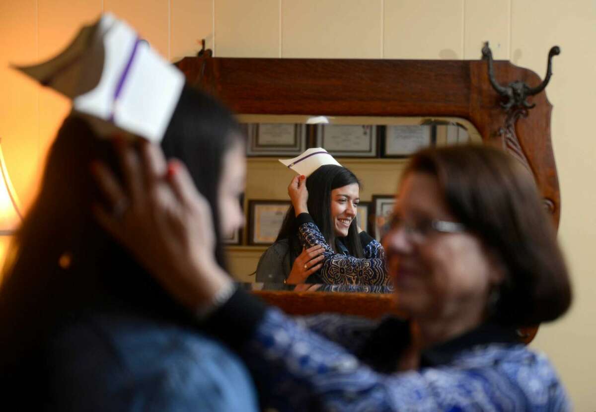 Kelly Olson tries on her mother, Lorraine nursing cap in the family room of their North Stamford home on April 26, 2016. Olson, 26, will fulfill her girlhood dream of becoming a nurse, like her mother, when she graduates from University of Bridgeport nursing school on Monday.