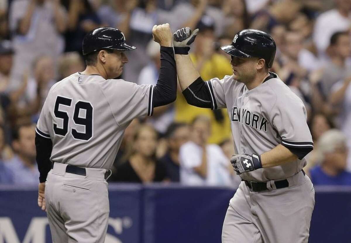 New York Yankees' Brian McCann, right, high-fives third base coach Rob Thomson (59) after hitting a fifth-inning home run off Tampa Bay Rays starting pitcher David Price during a baseball game on Thursday, April 17, 2014, in St. Petersburg, Fla. (AP Photo/Chris O'Meara)