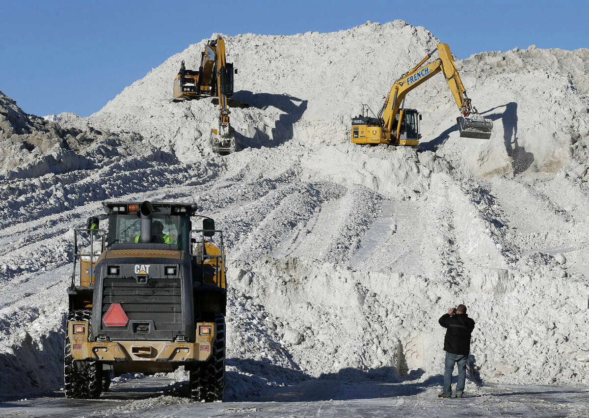 FILE - In this Feb. 16, 2015 file photo, heavy equipment works at a "snow farm" on a mound of snow from roads cleared in Boston. More than $1 billion was spent and 6 million tons of salt used to keep highways operating in nearly two dozen states during the recent harsh winter, according to a first-ever survey of state transportation officials. (AP Photo/Michael Dwyer, File)