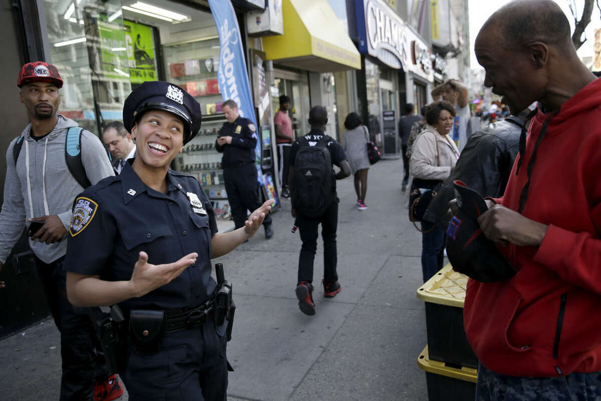 Police officer Lanora Moore talks with a man on 125th Street in the Harlem section of New York, Wednesday, April 29, 2015. (AP Photo/Seth Wenig)