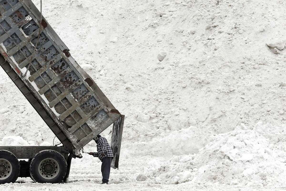 FILE - In this Feb. 14, 2015 file photo, Evon Daley, of Hartford, Conn., clears his truck after unloading plowed snow at a "snow farm" in Boston. More than $1 billion was spent and 6 million tons of salt used to keep highways operating in nearly two dozen states during the recent harsh winter, according to a first-ever survey of state transportation officials. (AP Photo/Michael Dwyer, File)