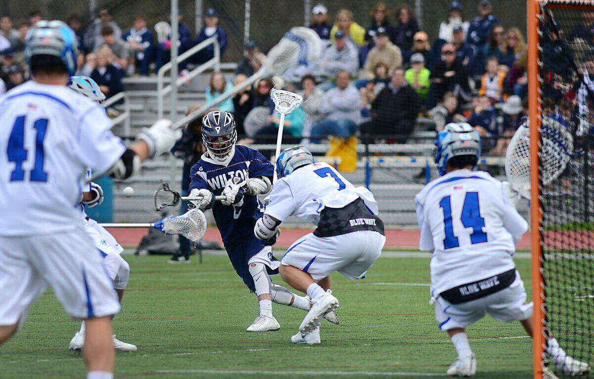 Wilton High School's Boys Lacrosse player #2 Brian Calabrese takes a shot on goal as Darien High School's #7, William Simpson, and goalie Ryan Cornell defend during their game on Saturday, April 22, 2016, at Darien High School in Darien, Conn.