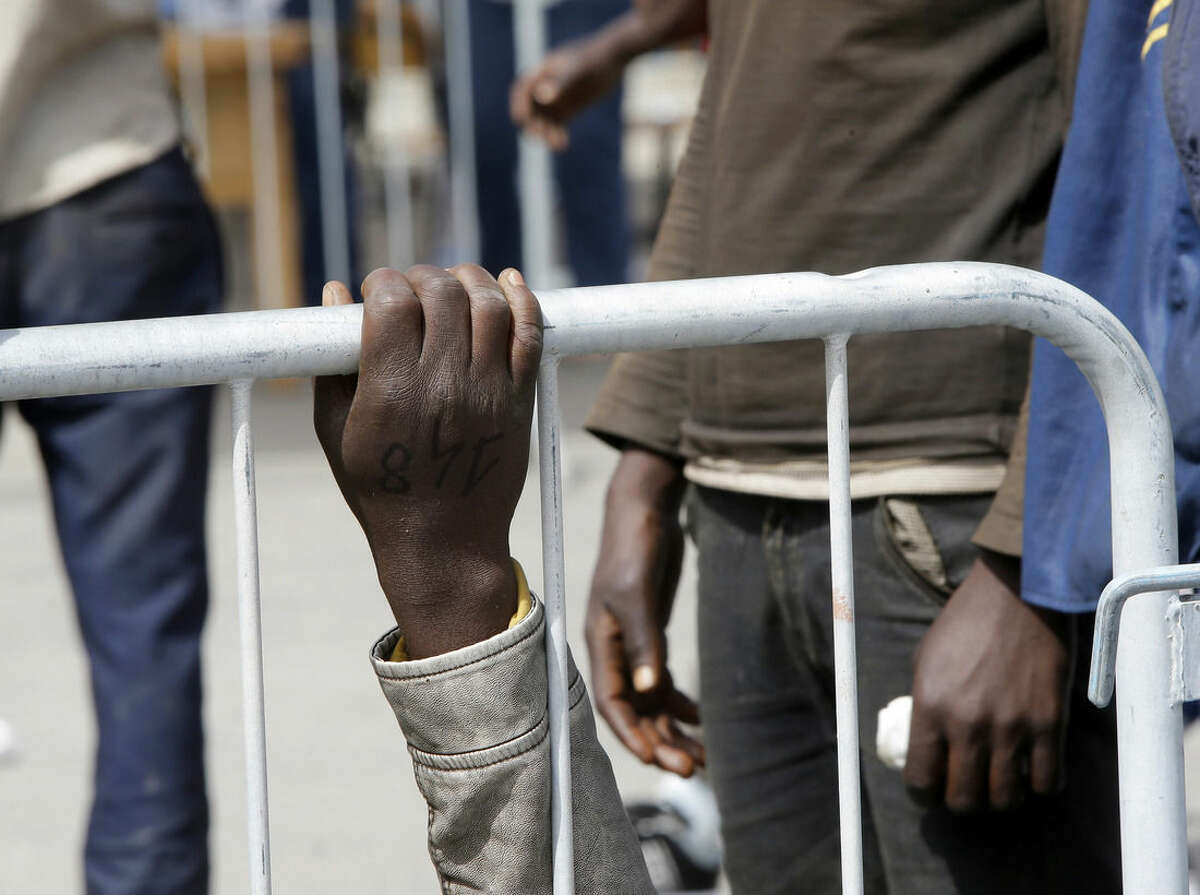 The hand of a migrant grasps a fence after arriving at the Catania harbor, Sicily, southern Italy, Tuesday, May 5, 2015. The arrivals are stretching Italy's already overtaxed migrant reception centers, with new arrivals being sent inland to be screened for asylum or in many cases, to continue on their journeys north unofficially. Dozens of passengers in a crowded rubber boat fell into the sea and likely drowned as a rescue vessel neared, survivors reported as they arrived in Italy Tuesday to join thousands of other migrants rescued in the Mediterranean in recent days. (AP Photo/Antonio Calanni)
