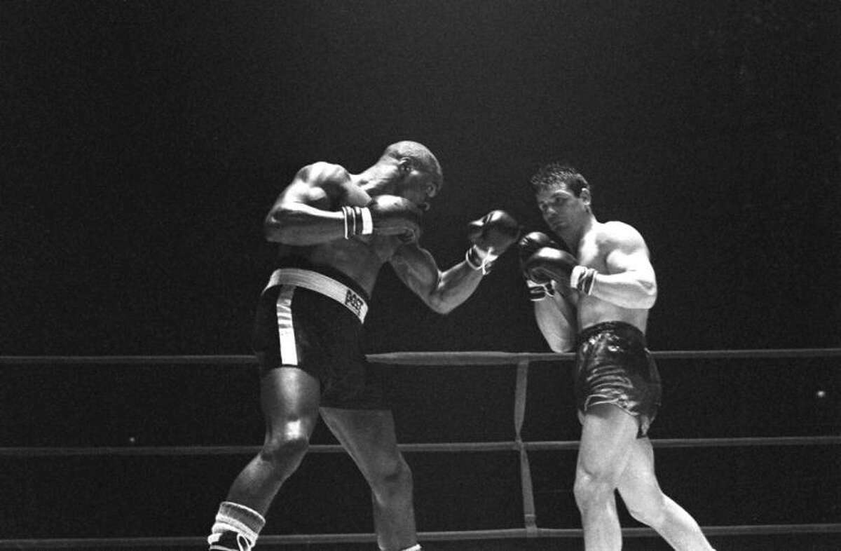 FILE - In this Feb. 23, 1965 file photo, Rubin "Hurricane" Carter, left, knocks out Italian boxer Fabio Bettini in the 10th and last round of their fight at the Falais Des Sports in Paris. Carter, who spent almost 20 years in jail after twice being convicted of a triple murder he denied committing, died at his home in Toronto, Sunday, April 20, 2014, according to long-time friend and co-accused John Artis. He was 76. (AP Photo/File)
