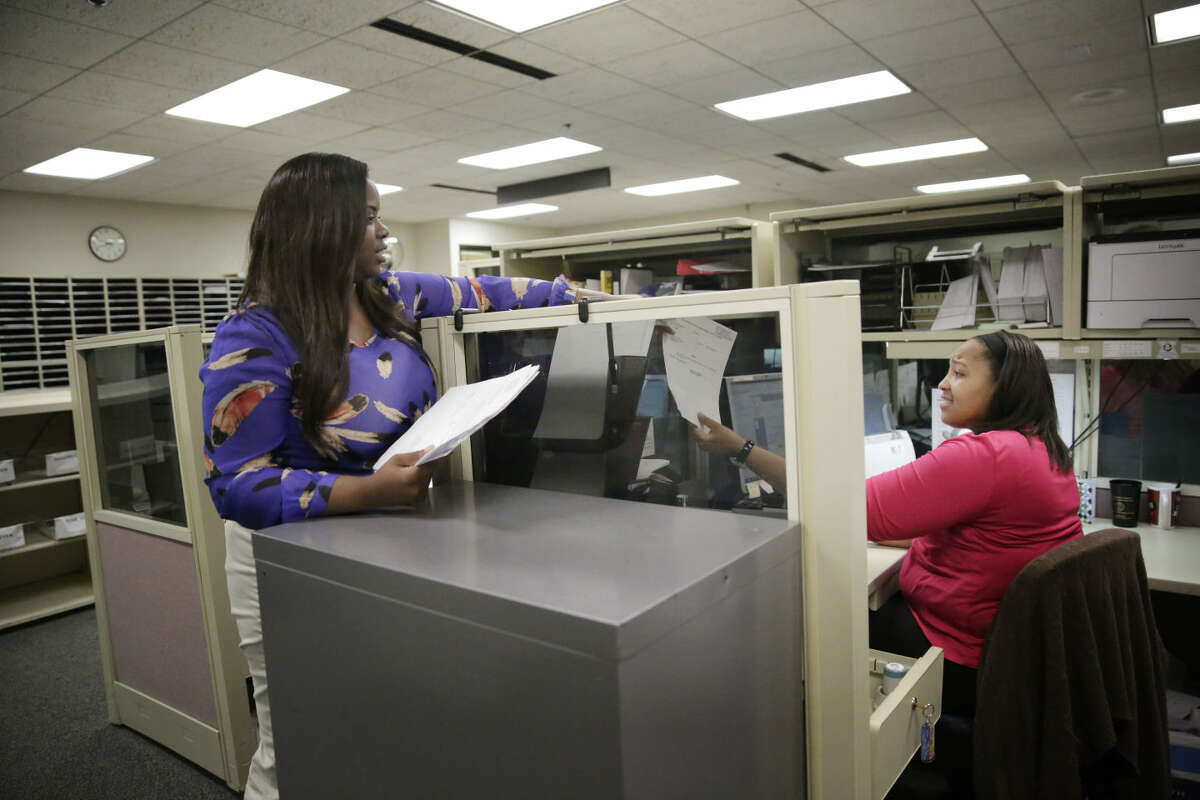 Trameka Daniels, left, hands Hillary Claibon, right, both of Montgomery, Ala., documents at the Alabama Circuit Court Clerk Criminal office, Thursday, May 7, 2015, in Montgomery, Ala. A trend is emerging among the states like Alabama showing large budget gaps. Shortfalls have been projected for the coming fiscal year in at least 22 states. (AP Photo/Brynn Anderson)