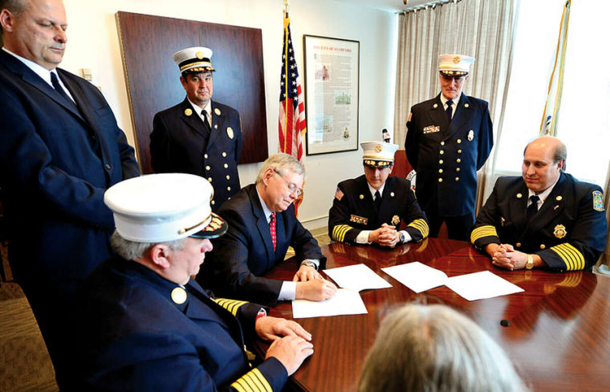 Hour photo / Erik Trautmann Mayor David Martin, Public Safety Director Ted Jankowski, Fire Chief Peter Brown, Turn Of River (TOR) Chief Frank Jacobellis, TOR Assistant Chief Matt Maounis, and TOR President Nicholas Jossem sign the agreement to consolidate the City and Turn of River Volunteer Fire Departments during a press conference Wednesday..