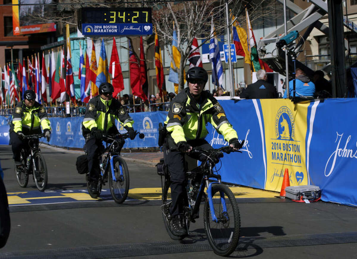 Boston Police officers on bicycles ride across the finish line before during 118th Boston Marathon Monday, April 21, 2014 in Boston. (AP Photo/Elise Amendola)
