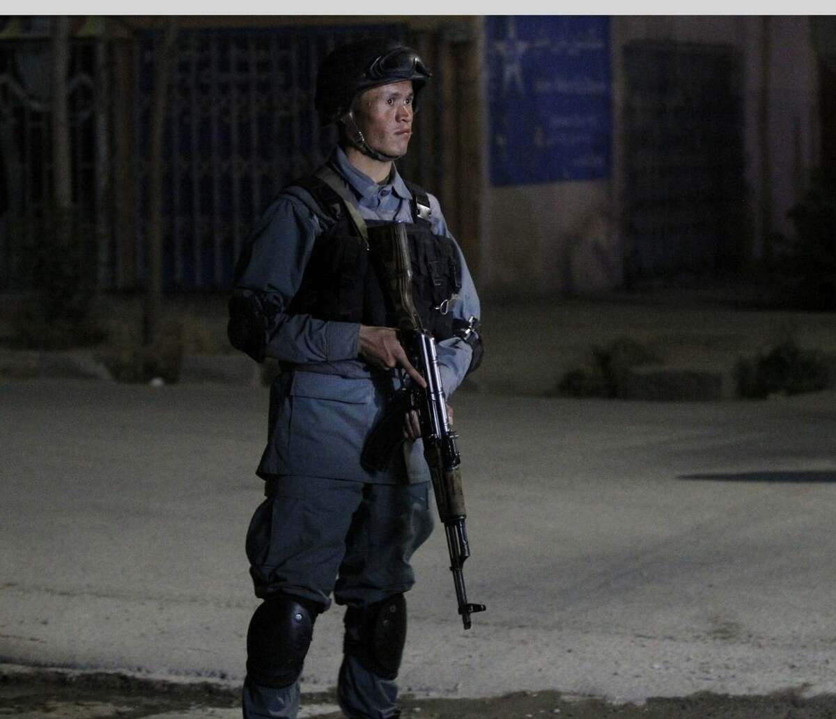 An Afghan policeman stands guard by the Park Palace Hotel after an attack by Taliban militants, in Kabul, Afghanistan, Wednesday, May 13, 2015. Gunmen have stormed a guesthouse in the Afghan capital used by both foreigners and locals, sparking a gun battle with police The attackers targeted Kabul's Park Palace Hotel on Wednesday night Kabul police chief Gen. Abdul Rahman Rahimi says the gunmen were still shooting at his officers. (AP Photo/Allauddin Khan)