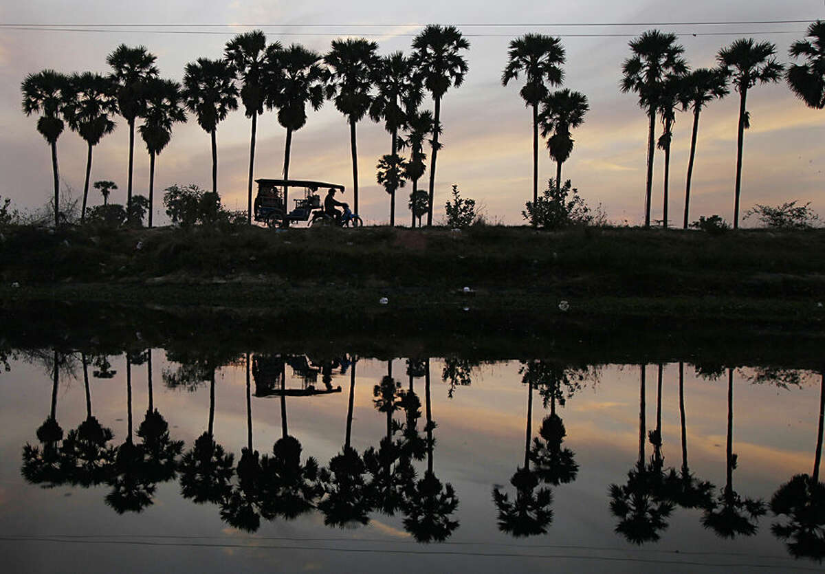 A man drives a motor cart at dawn as he takes passengers into town from the outskirts of Phnom Penh, Cambodia, Thursday morning, May 14, 2015. Motorcycle-based transportation continues to be popular in the developing nation due to their relative low cost and fuel-efficiency despite the increase in automobile use in recent years. (AP Photo/Heng Sinith)