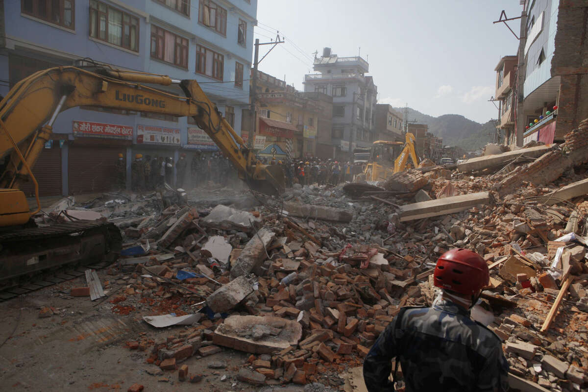 Earthmovers clear the debris at the site of a building that collapsed in an earthquake in Kathmandu, Nepal, Tuesday, May 12, 2015. A major earthquake has hit Nepal near the Chinese border between the capital of Kathmandu and Mount Everest less than three weeks after the country was devastated by a quake. (AP Photo/Niranjan Shrestha)
