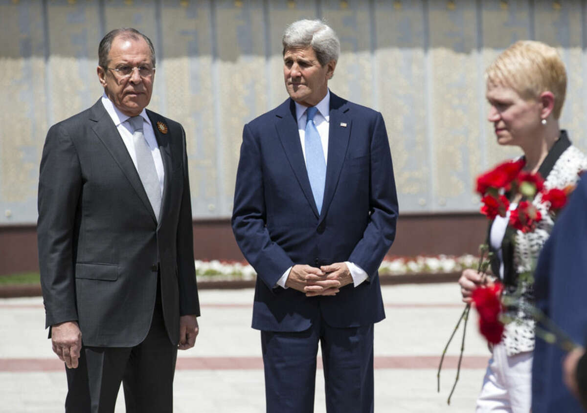 U.S Secretary of State John Kerry and Russian Foreign Minister Sergey Lavrov, left, watch as members of the United States and Russian delegations place red flowers at the Zakovkzalny War Memorial in Sochi, Russia, Tuesday May 12, 2015. Kerry is in Russia to meet President Vladimir Putin with an eye on easing badly strained relations over conflicts in Ukraine and Syria. (Joshua Roberts/Pool Photo via AP)