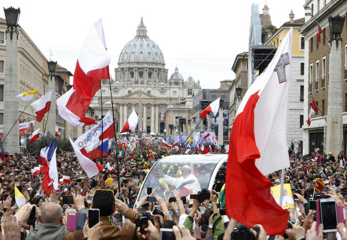 Pope Francis greets faithful as he is driven through the crowd along Via della Conciliazione after celebrating the ceremony for the canonizations of Pope John XXIII and Pope John Paul II in St. Peter's Square, at the Vatican, Sunday, April 27, 2014. Pope Francis declared his two predecessors John XXIII and John Paul II saints before some 800,000 people on Sunday, an unprecedented ceremony made even more historic by the presence in St. Peter's Square of emeritus Pope Benedict XVI. (AP Photo/Riccardo De Luca)