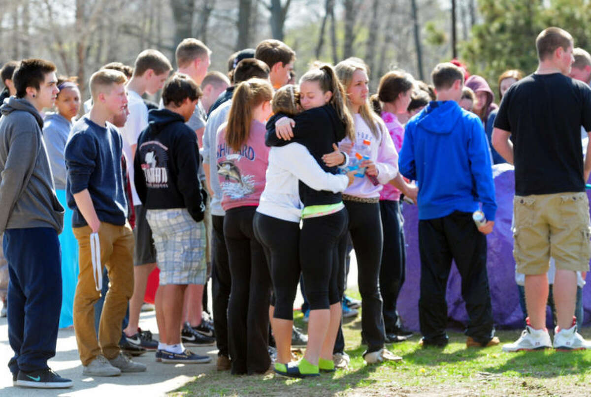 Students hug and spray paint a rock purple outside Jonathan Law High School in Milford, Conn., Friday, April 25, 2014, in memory of 16-year-old stabbing victim Maren Sanchez. Sanchez was stabbed to death earlier in the day during an altercation inside the school. A teenage boy is in custody, and police are investigating whether she was stabbed because she declined to be his date at the junior prom. (AP Photo/The New Haven Register, Peter Hvizdak) MANDATORY CREDIT