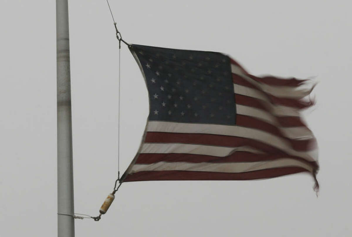 A flag is tattered in the wind of a severe thunderstorm at a farm credit office near Baldwin City, Kan., Sunday, April 27, 2014. Severe storms are expected in the area most of the day. (AP Photo/Orlin Wagner)