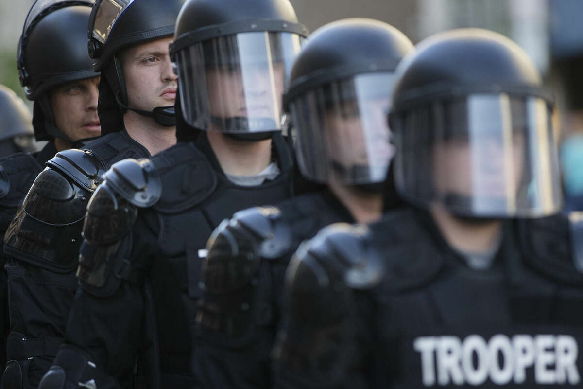 FILE - In this May 23, 2015, file photo, riot police stand in formation as a protest forms against the acquittal of Michael Brelo, a patrolman charged in the shooting deaths of two unarmed suspects in Cleveland. The city of Cleveland has reached a settlement with the U.S. Justice Department over a pattern of excessive force and civil rights violations by its police department, and the agreement could be announced as soon as Tuesday, May 26, 2015, a senior federal law enforcement official said. (AP Photo/John Minchillo, File)