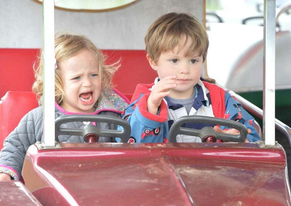 Hour Photo/Alex von Kleydorff Carys Rader is unsure of her older brother Henry's driving as the two set off on the roudabout cars at The Rowayton carnival on Friday Night