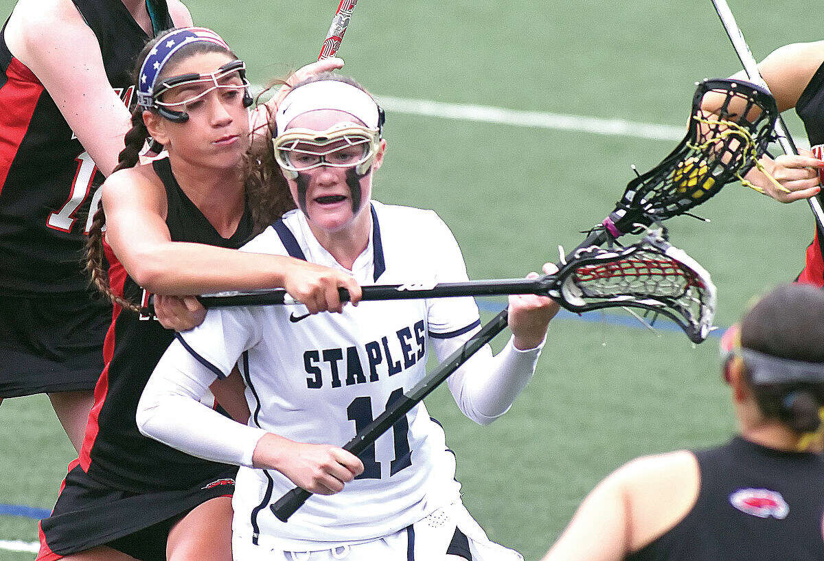 Staples High School’s Colleen Bannon, front, finds herself getting checked from behind while making a rush toward goal during the second half of Monday’s CIAC Class L girls lacrosse state tournament game in Westport. The host Wreckers topped the Mustangs 11-8. (Hour photo/John Nash)