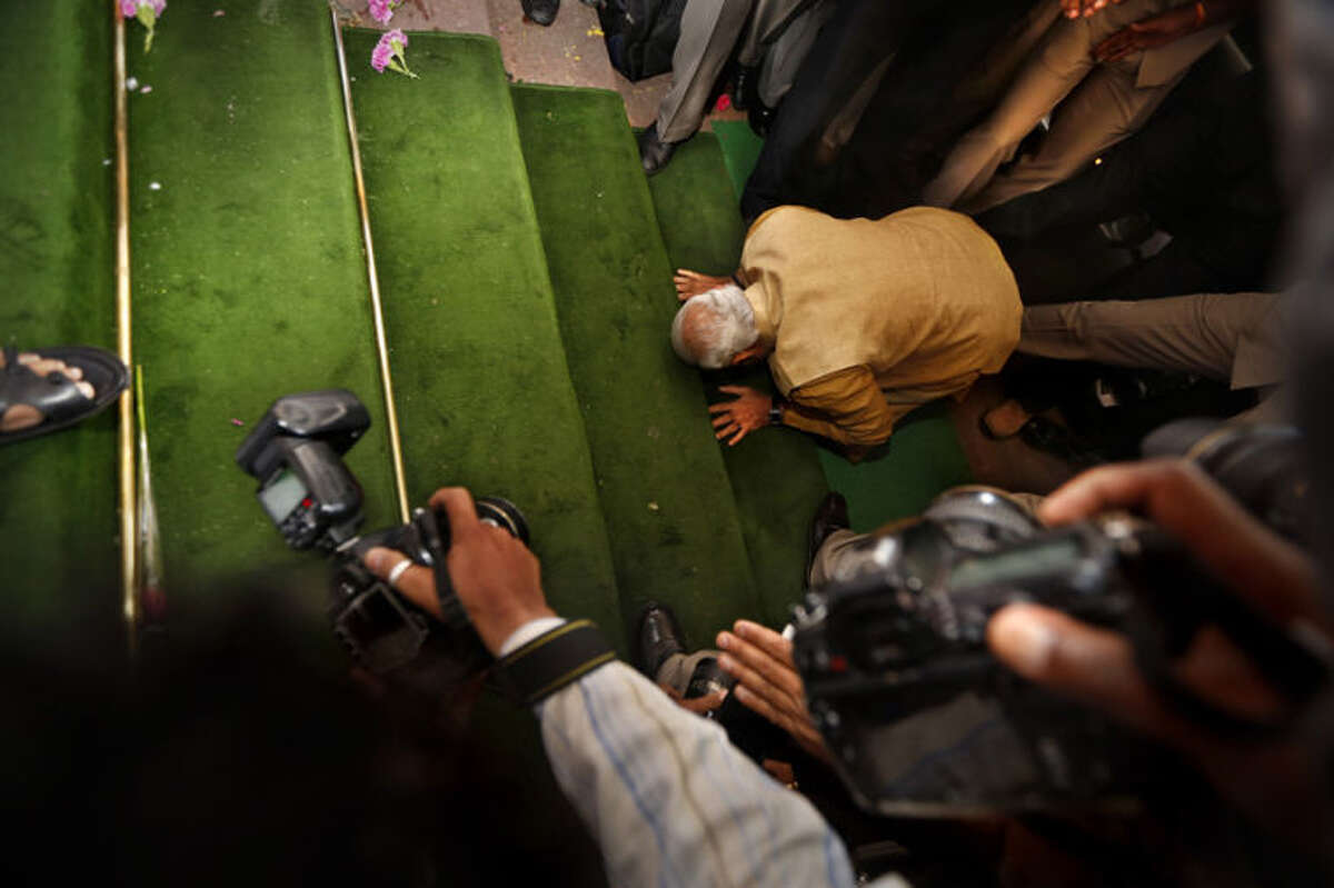 India's next prime minister and Hindu nationalist Bharatiya Janata Party (BJP) leader Narendra Modi, bends down on his knees on the steps of the Indian parliament building as a sign of respect as he arrives for the BJP parliamentary party meeting in New Delhi, India, Tuesday, May 20, 2014. The BJP has started putting together a new government by formally choosing Modi to be the country's next prime minister following a resounding victory in national elections. (AP Photo/Manish Swarup)