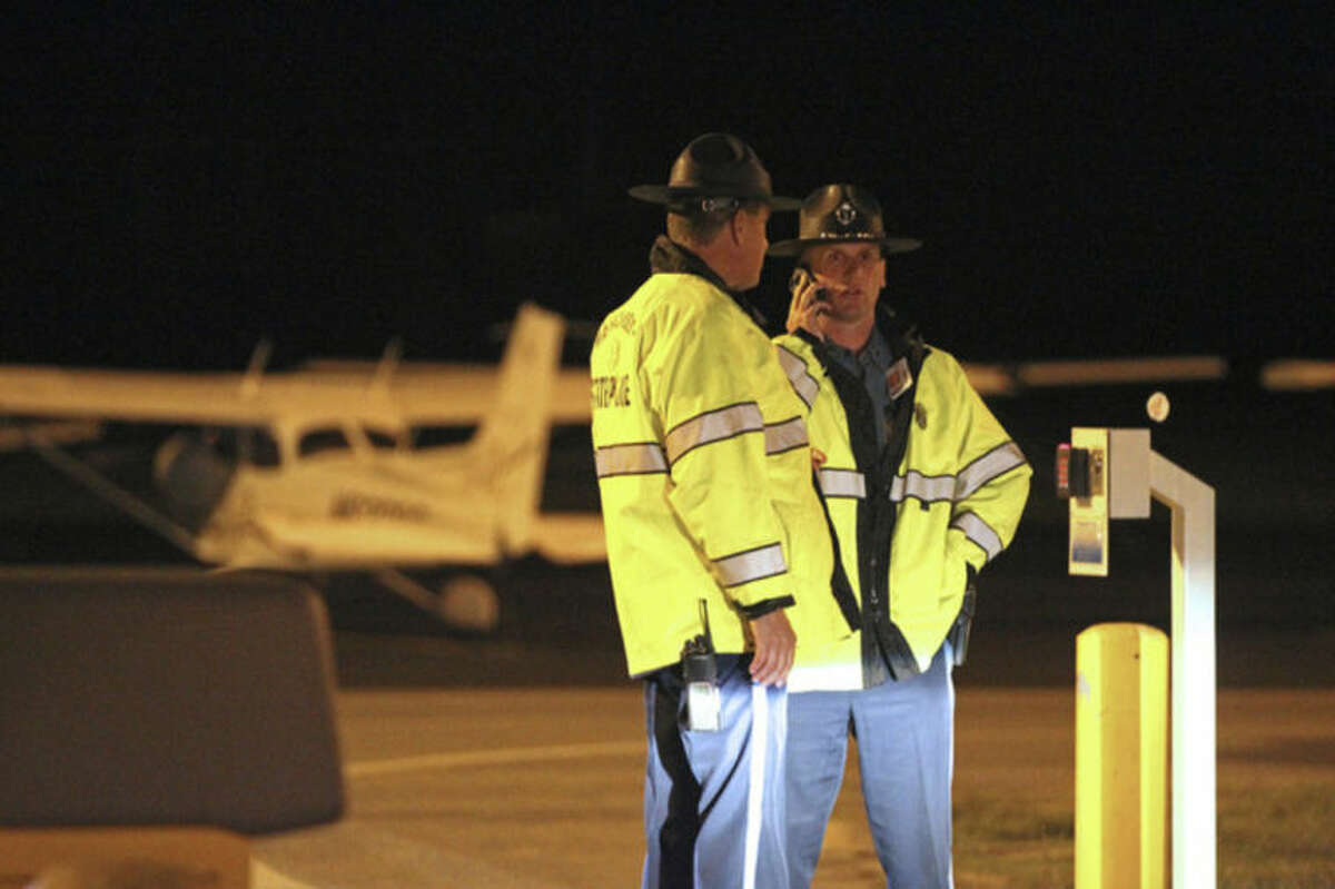 State Police stand at the gate of Hanscom Field where a private Gulfstream IV plane with seven people aboard crashed and caught fire late Saturday, May 31, 2014. (AP Photo/The Boston Herald, Stuart Cahill