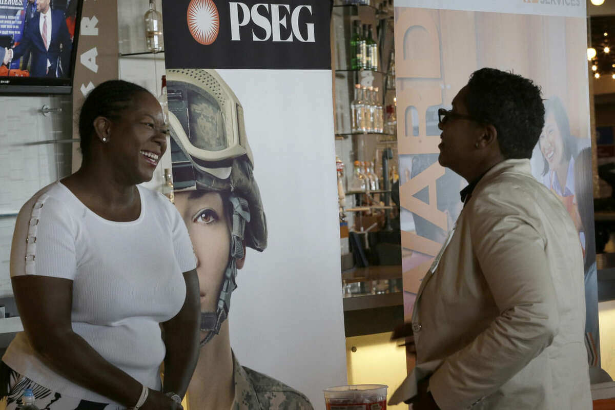 In this photo taken Tuesday, June 30, 2015, Sophia Lewis, left, with PSEG Long Island, speaks to an attendee about employment opportunities during a job fair at Citi Field in New York. U.S. employers likely hired at another strong pace in June, a sign that the job market is nearing full health and giving the Federal Reserve reason to raise interest rates as early as September. Economists predict that employers added 233,000 jobs and that the unemployment rate dipped to 5.4 percent from 5.5 percent in May, according to data firm FactSet. (AP Photo/Mary Altaffer)