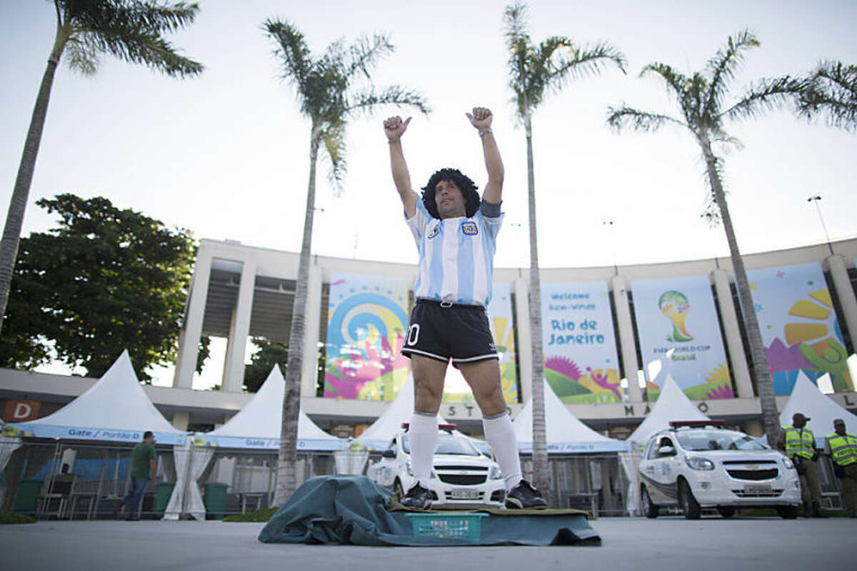 Street performing mime, Daniel Gonzalez, 35, who is dressed to resemble Argentine soccer great Diego Armando Maradona, gestures to the people who walk past him, in front of Maracana stadium, Rio de Janeiro, Brazil, Wednesday, June 11, 2014. The World Cup soccer tournament starts Thursday. (AP Photo/Leo Correa)