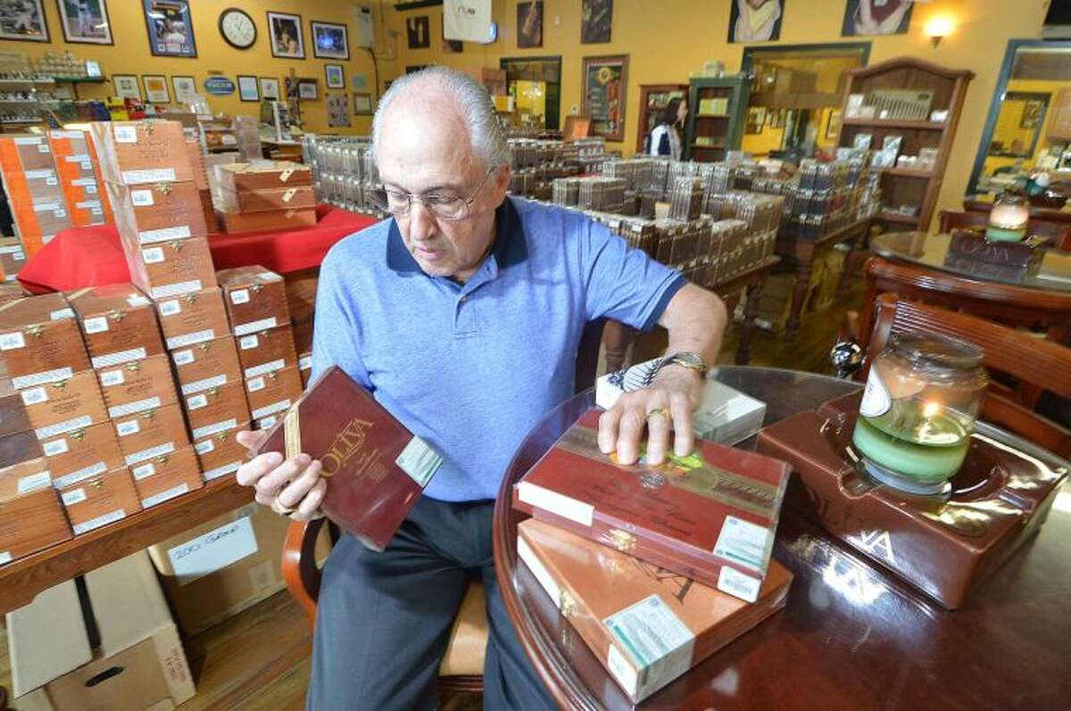 Hour Photo/Alex von Kleydorff Ron Shapiro , Owner of International Cigar Facory Outlet places some of the boxes of cigars for Fathers day, on a table near the lounge area and showroom in his Hanford Place store . Since 1932 the family run business stocks hundreds of different types of cigars along with Humidors, accesories and all things related, and can ship anywhere