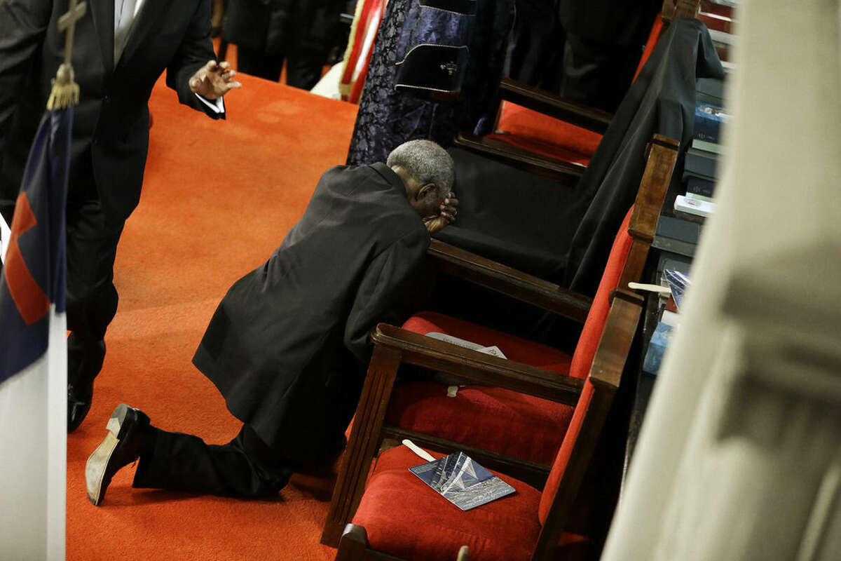 A parishioner prays at the empty seat of the Rev. Clementa Pinckney at the Emanuel A.M.E. Church four days after a mass shooting that claimed the lives of Pinckney and eight others on Sunday, June 21, 2015, in Charleston, S.C. (AP Photo/David Goldman, Pool)