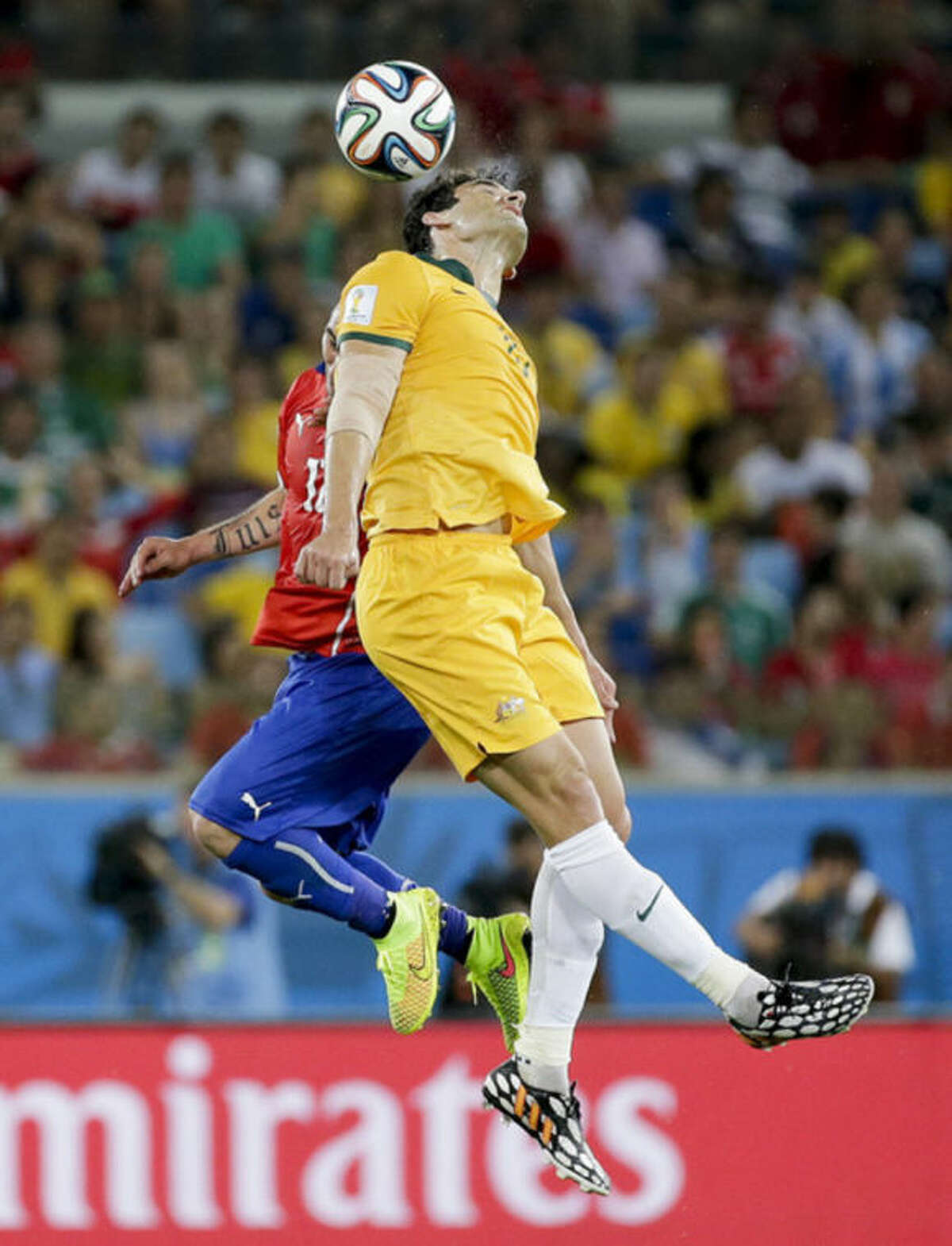 Australia's Mile Jedinak, front, rises above Chile's Gary Medel to win a header during the group B World Cup soccer match between Chile and Australia in the Arena Pantanal in Cuiaba, Brazil, Friday, June 13, 2014. (AP Photo/Felipe Dana)