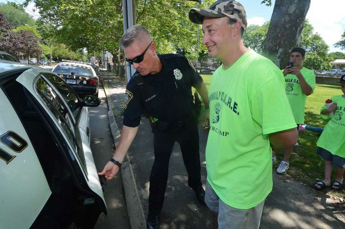 Hour Photo/Alex von Kleydorff Norwalk Police Officer Chris Holms is handcuffed and taken into custody by fellow officer Fred Kellogg during the 2014 MDA Lock Up to raise money for Muscular Dystrophy Association