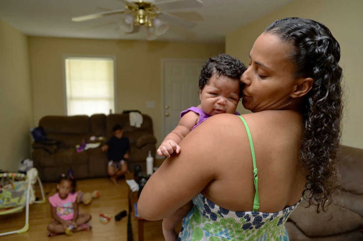 In this June 18, 2014 photo, Army Sgt. LaQuisha Gallmon holds her 2-month-old Abbagayl, as her children Dallin, 8, and Angelicah, 5, sit in their home in Greenville, S.C. Gallmon said that her local VA office had authorized her to see a private physician during her pregnancy, so she went to an emergency room after experiencing complications in her sixth month of pregnancy. She said the VA has thus far refused to pay the resulting $700 bill. (AP Photo/ Richard Shiro)