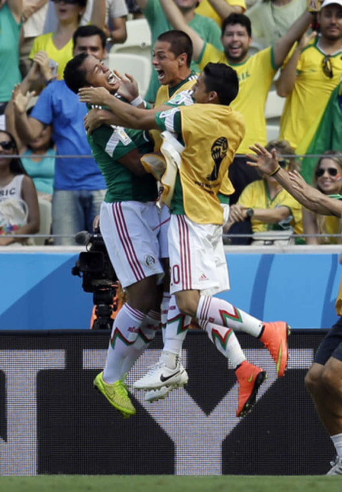 Mexico's Giovani dos Santos, left, celebrates after scoring the opening goal during the World Cup round of 16 soccer match between the Netherlands and Mexico at the Arena Castelao in Fortaleza, Brazil, Sunday, June 29, 2014. (AP Photo/Natacha Pisarenko)