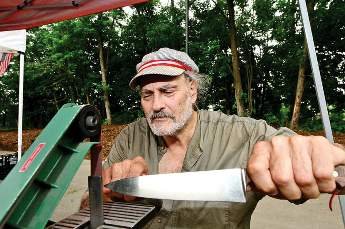 Hour photo / Erik Trautmann Nick " The Knife" Jacobs shapens knives at the annual Westport Farmers' Market Thursday morning.