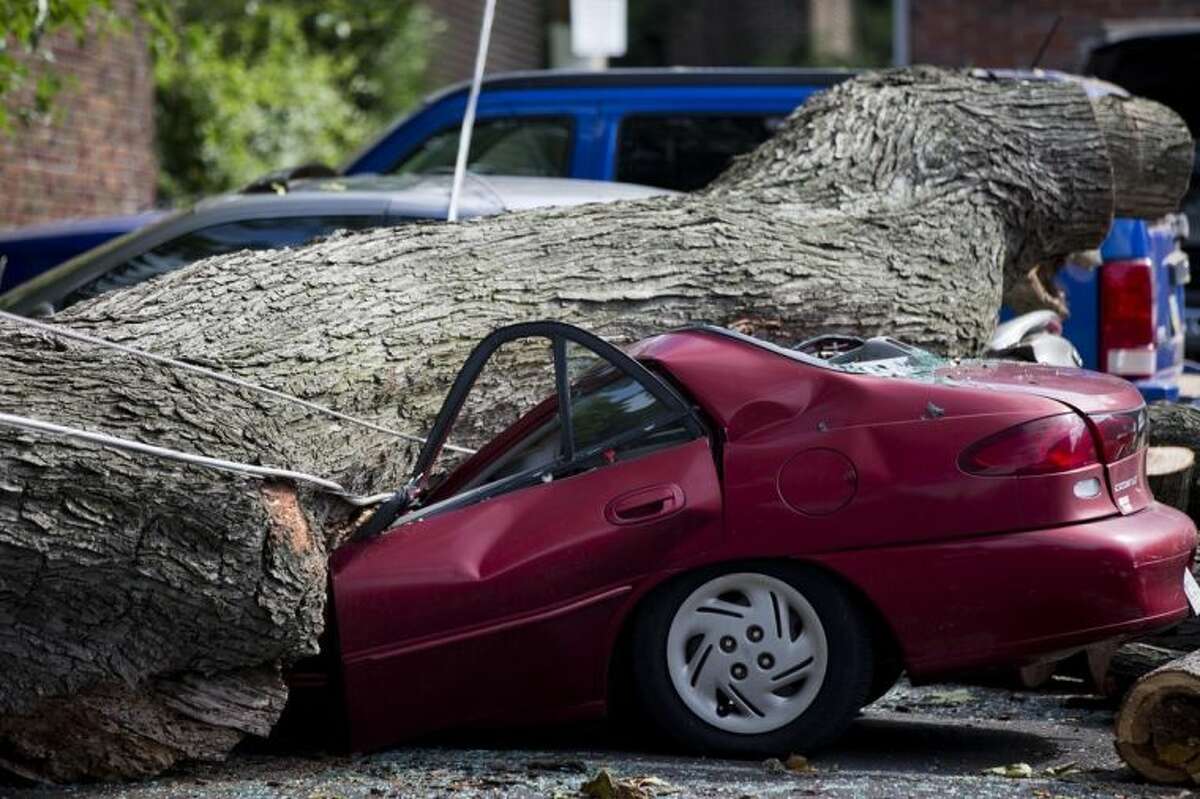 A downed tree lays atop a crushed car Wednesday, July 9, 2014, in Philadelphia. About 228,000 homes and businesses across Pennsylvania remain without power after severe thunderstorms raced across the state. (AP Photo/Matt Rourke)