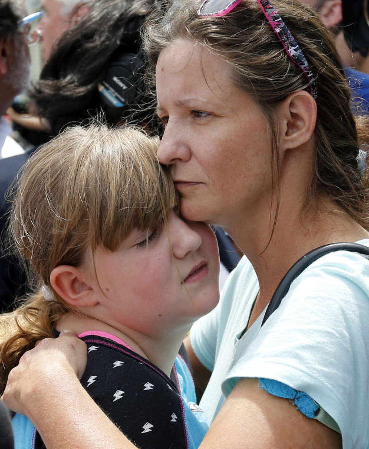 Geri Boyles of Lowell, Mass. hugs her daughter, Corinna, 10, outside a burned three-story apartment and business building in Lowell, Thursday, July 10, 2014. The neighbors lost people they knew in the fast-moving pre-dawn fire where officials said seven people died. (AP Photo/Elise Amendola)