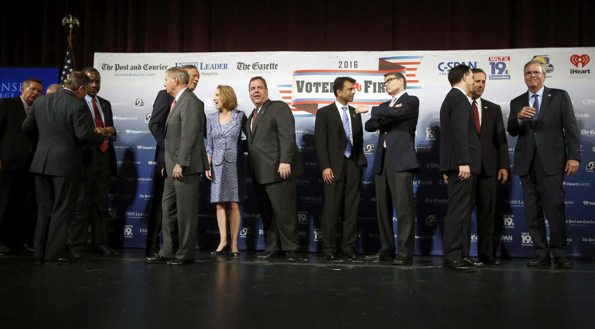 Republican presidential candidates John Kasich, left, Ben Carson, third from left, Lindsey Graham, George Pataki, Carly Fiorina, Chris Christie, Bobby Jindal, Rick Perry, Scott Walker, Rick Santorum and Jeb Bush speak among themselves after a forum Monday, Aug. 3, 2015, in Manchester, N.H. Second from left is Saint Anselm College president Steven DiSalvo. (AP Photo/Jim Cole)