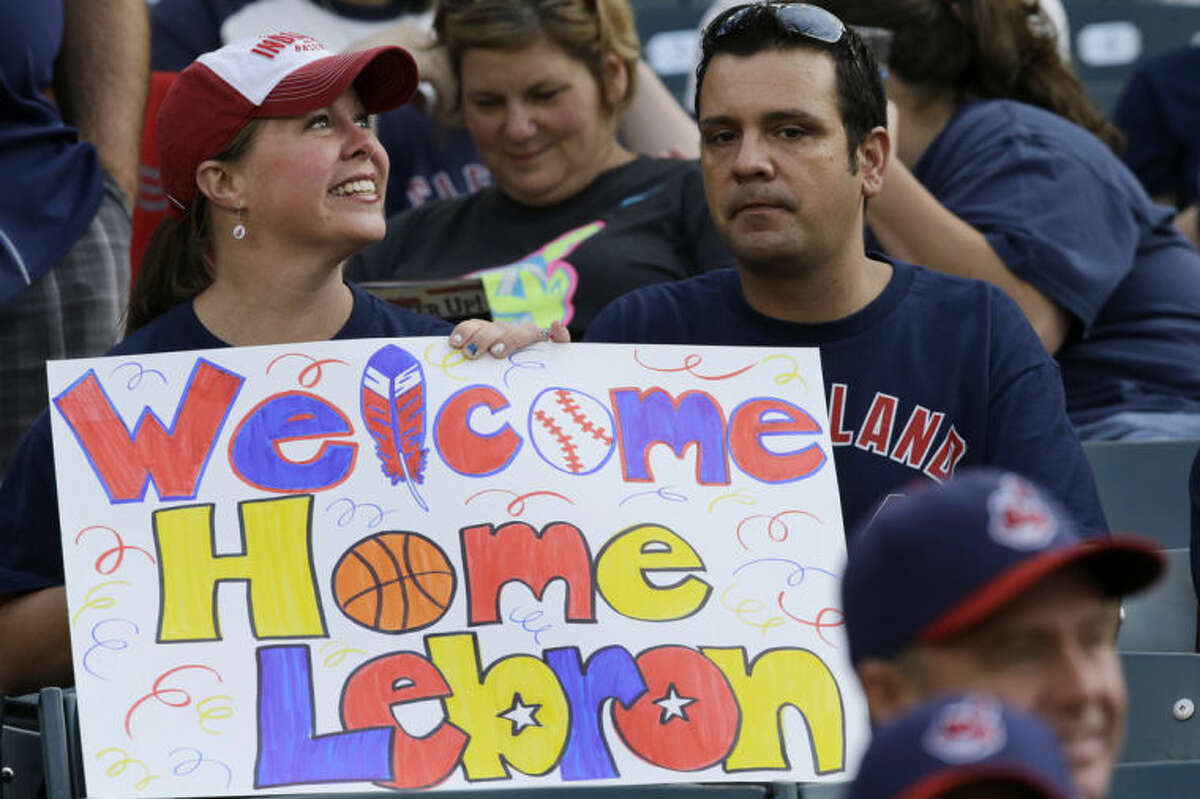 A fan holds a sign welcoming LeBron James back to Cleveland, before a baseball game between the Chicago White Sox and Cleveland Indians on Friday, July 11, 2014, in Cleveland. James announced earlier in the day he will return to play for the Cleveland Cavaliers. (AP Photo/Mark Duncan)
