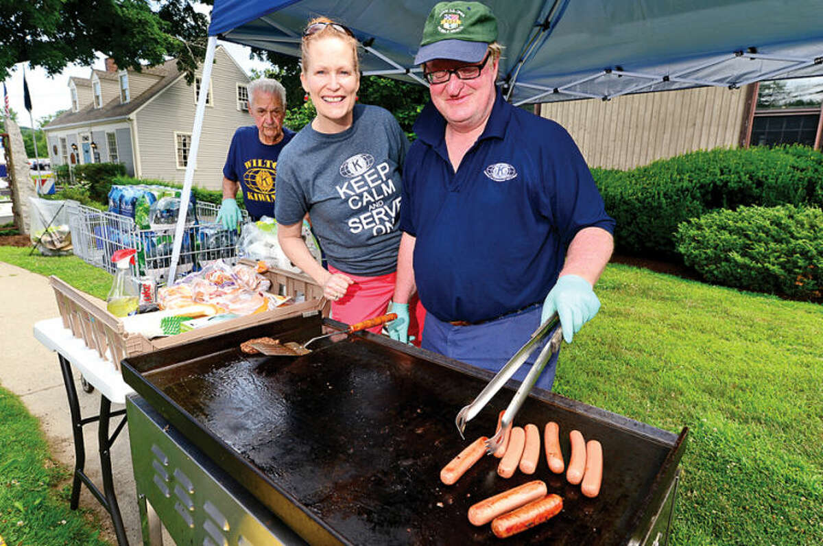 Hour photo / Erik Trautmann Nancy Pantoliano and Dan Mahony of the Kiwanis Club cook up hot dogs during the 3rd annual Wilton Street Fair and Sidewalk Sale in Wilton Center Saturday.