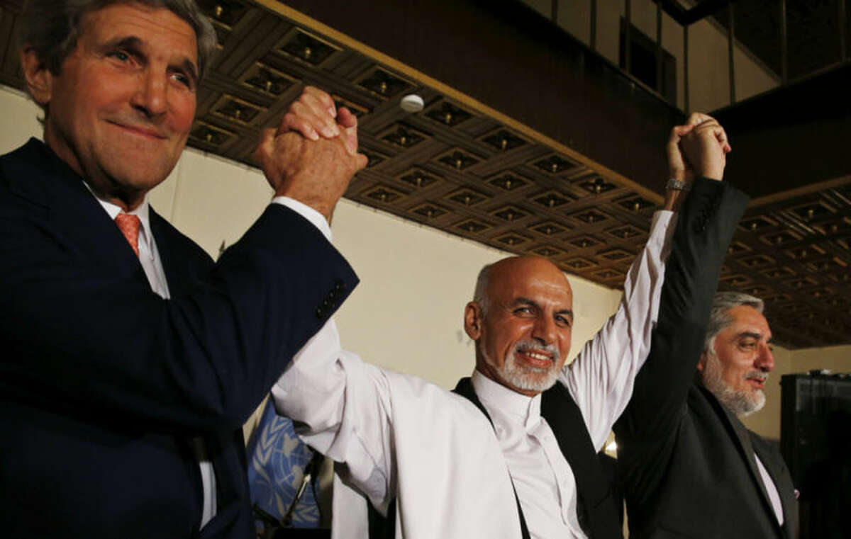 U.S. Secretary of State John Kerry, left, and Afghanistan's presidential candidates Ashraf Ghani, centre, and Abdulah Abdullah hold their arms in the air together after announcing a deal for the auditing of all Afghan election votes at the United Nations Compound in Kabul, Saturday, July 12, 2014. (AP Photo/Jim Bourg, Pool)