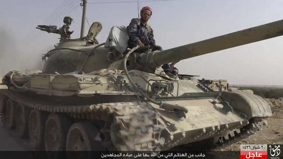 In this picture released Wednesday, Aug. 5, 2015 by the Rased News Network a Facebook page affiliated with Islamic State militants, an Islamic State militant sits on a tank they captured from Syrian government forces, in the town of Qaryatain southwest of Palmyra, central Syria. The Islamic State group on Thursday seized a key town in central Syria following heavy clashes with President Bashar Assad's forces, in the militants' biggest advance since capturing the historic town of Palmyra in May, Syrian activists said. (Rased News Network a Facebook page affiliated with Islamic State militants via AP)