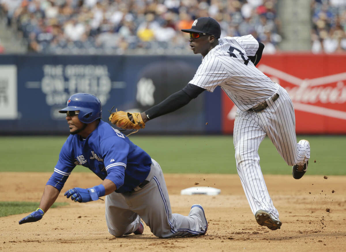 New York Yankees shortstop Didi Gregorius makes a double play as he tags out Toronto Blue Jays' Edwin Encarnacion between first and second base before flipping the ball to first for the force out on Toronto Blue Jays Justin Smoak during the eighth inning of a baseball game, Saturday, Aug. 8, 2015, in New York. (AP Photo/Julie Jacobson)