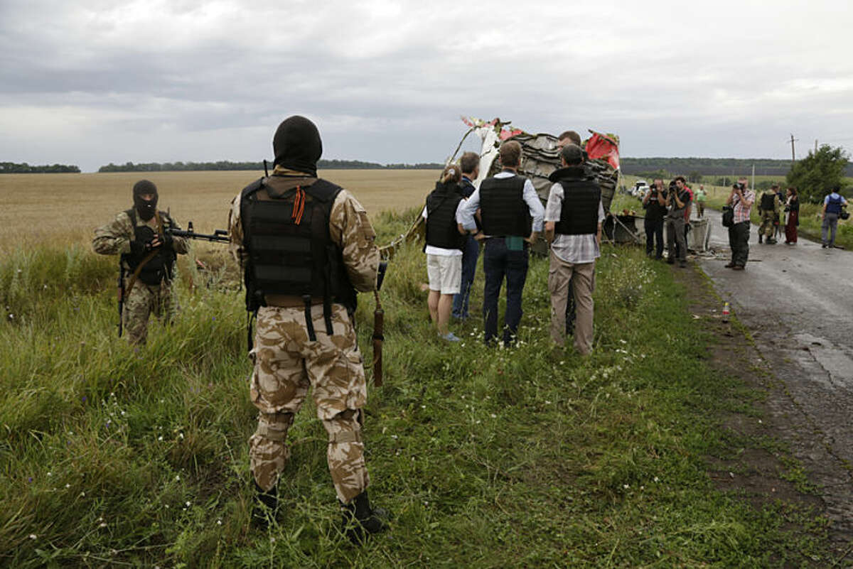 Pro-Russia fighters sedure the area as the OSCE (Organization for Security and Co-operation in Europe) delegation, at centre, arrives at the crash site of a Malaysia Airlines jet near the village of Hrabove, eastern Ukraine, Friday, July 18, 2014. Representatives from OSCE and four Ukrainian experts have traveled into rebel-controlled areas to begin an investigation into the downing of the Malaysia Airlines plane on Wednesday and the deaths of all its passengers and crew. (AP Photo/Dmitry Lovetsky)