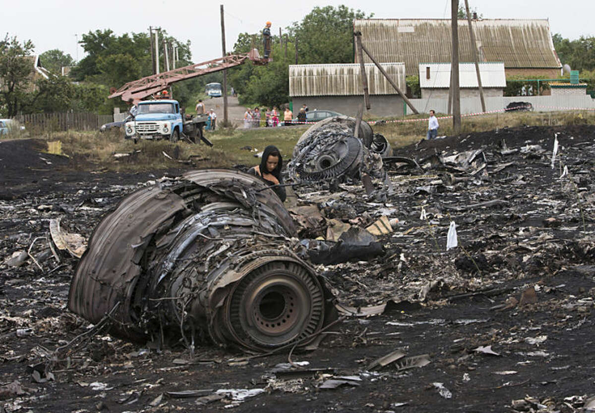A woman walks at the site of a crashed Malaysia Airlines passenger plane near the village of Rozsypne, eastern Ukraine Friday, July 18, 2014. Rescue workers, policemen and even off-duty coal miners were combing a sprawling area in eastern Ukraine near the Russian border where the Malaysian plane ended up in burning pieces Thursday, killing all 298 aboard. (AP Photo/Dmitry Lovetsky)