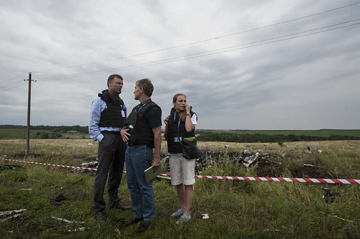 Alexander Hug, left, deputy head of the OSCE mission, stands at the crash site of a Malaysia Airlines jet near the village of Hrabove, eastern Ukraine, Friday, July 18, 2014. Representatives from the Organization for Security and Cooperation in Europe and four Ukrainian experts had traveled into rebel-controlled areas to begin an investigation into the attack that killed 298 people from nearly a dozen nations. The militia allowed them to look at part of the crash site, but refused to let them view the area where the engines came down. (AP Photo/Evgeniy Maloletka)